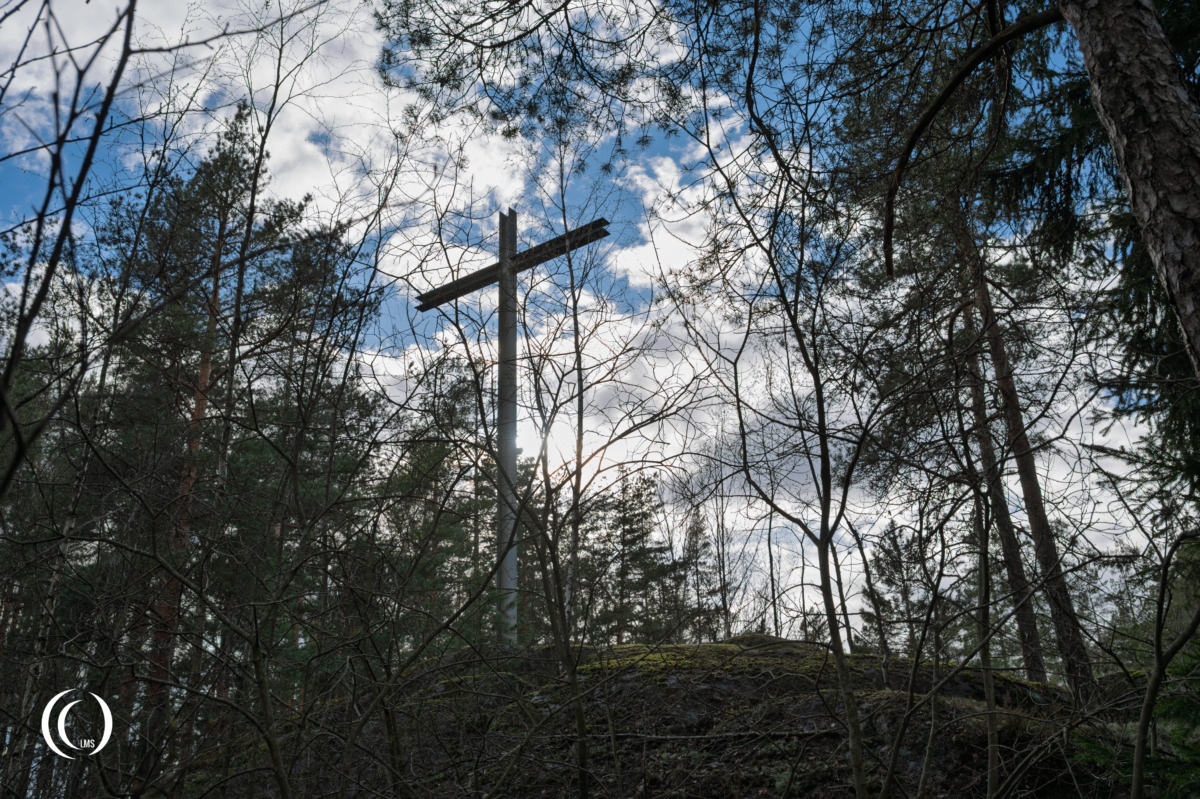 Steel high cross erected on a rocky outcrop of German War Cemetery Helsinki-Honkanummi in Finland